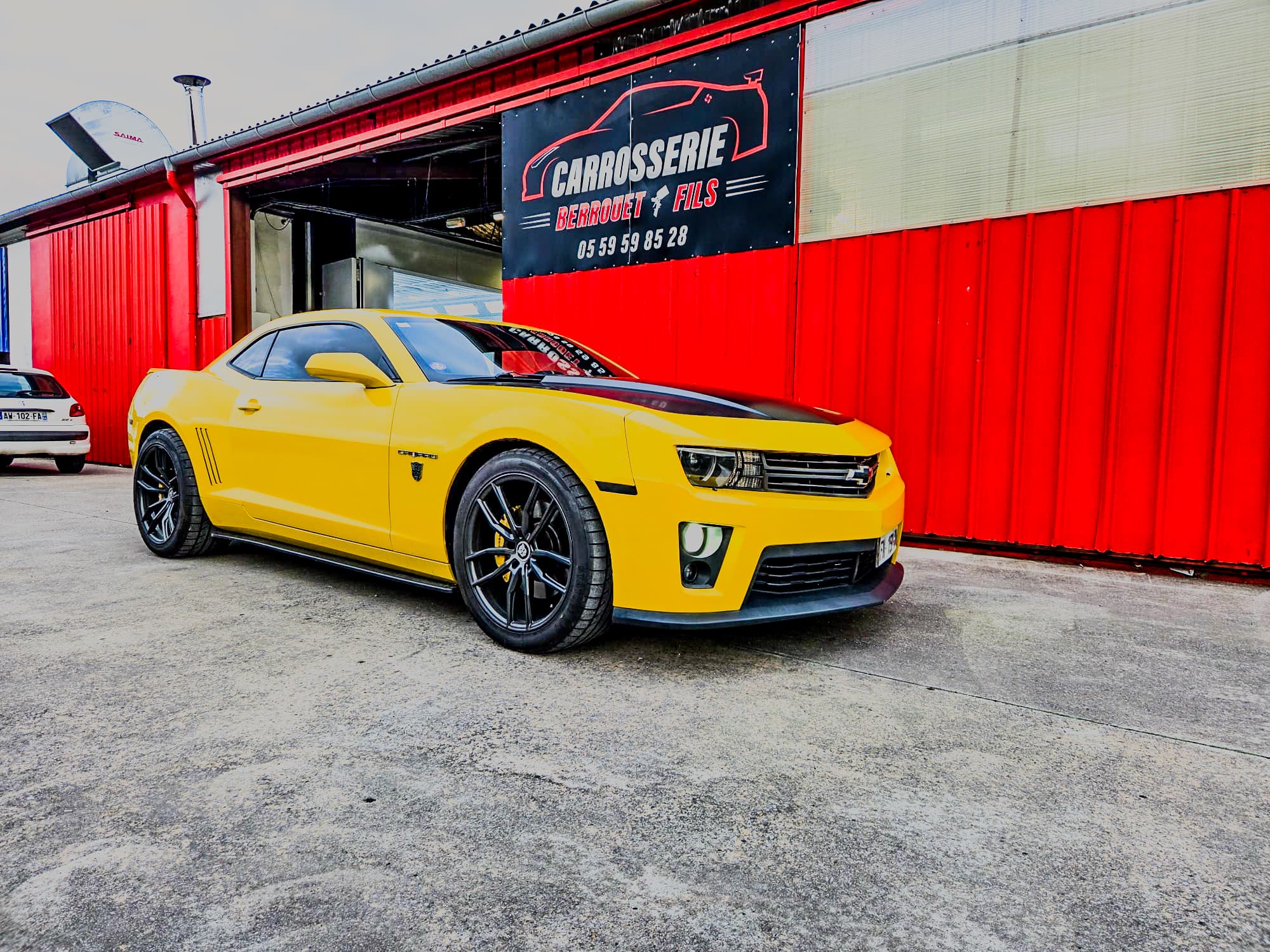 Chevrolet Camaro jaune devant l'atelier de la Carrosserie Berrouet.